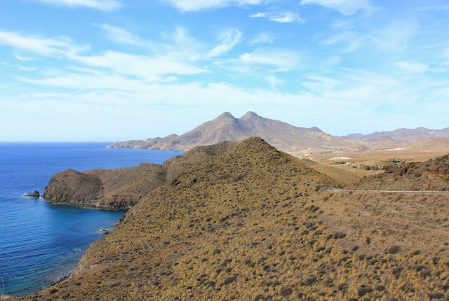 Widok na wulkaniczne bliźniacze stożki zwane Los Frailes. Szare, gołe, niemal pustynne zbocza, które klifami wciskają się w osto błękitne wody Morza Śródziemnego.