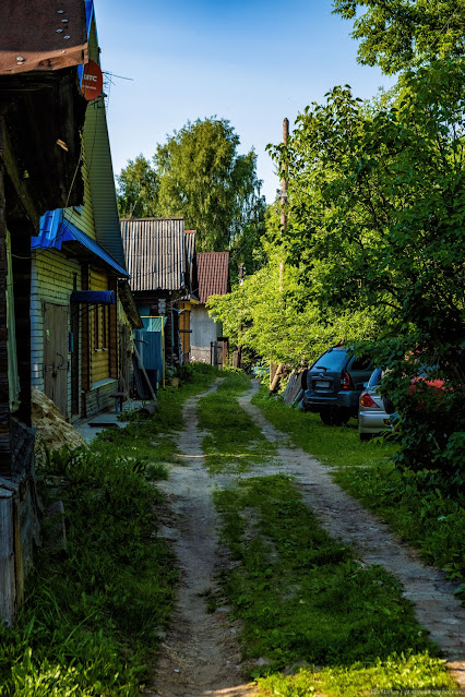 Деревенская улица с домами и припаркованными машинами