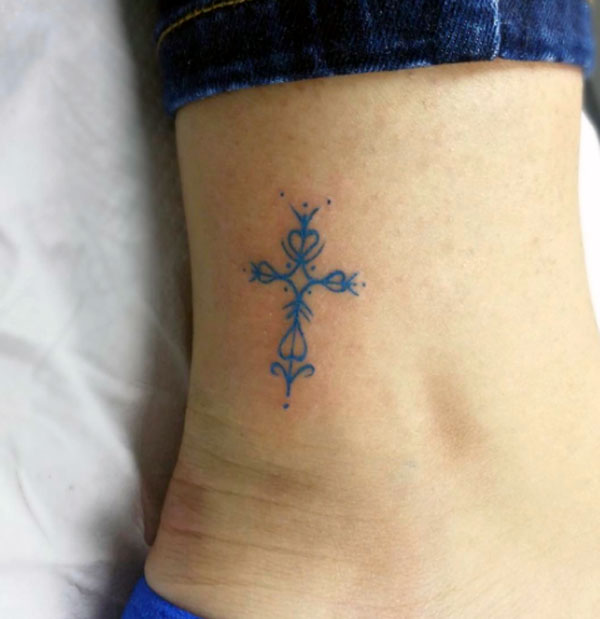 Small and cute ornate cross tattoo design blue ink work gives your ankle a nice look