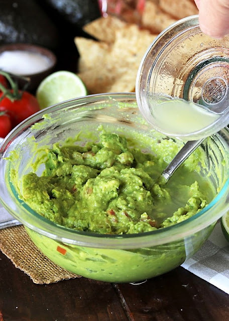 Adding Lime Juice To a Bowl of Homemade Guacamole Image