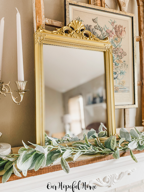 gold frame on mantel with botanical framed print  and white taper candle