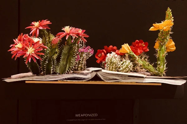 paper sculpture of two colorful cacti flower arrangements positioned on back of open hardback book