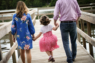 Mom, dad and daughter walking towards the end of a doc.