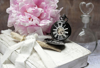 Book on a table with flowers and a timepiece