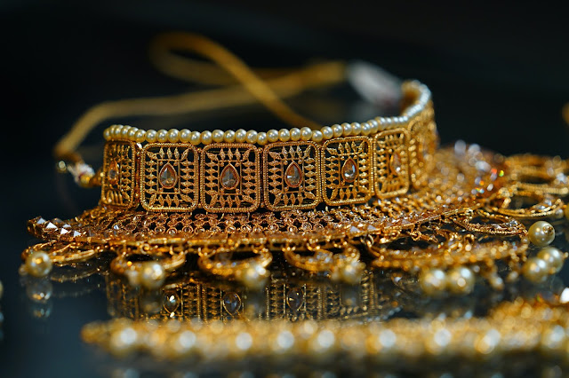 Fine golden jewelry laid out for display on top of a black marble surface.