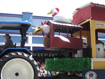 A tractor pulling a float with a flying chicken