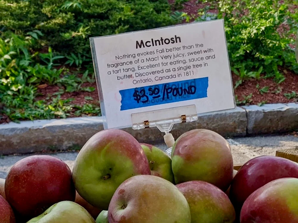 A pile of red apples and a small sign that reads "McIntosh, $3.50 per pound"