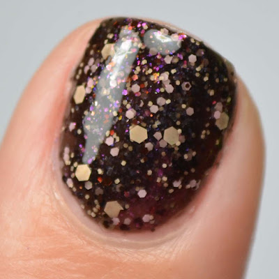 black nail polish with peach and pink glitter swatch