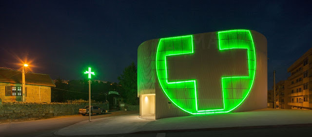 Green pharmacy logo made of light on the modern building