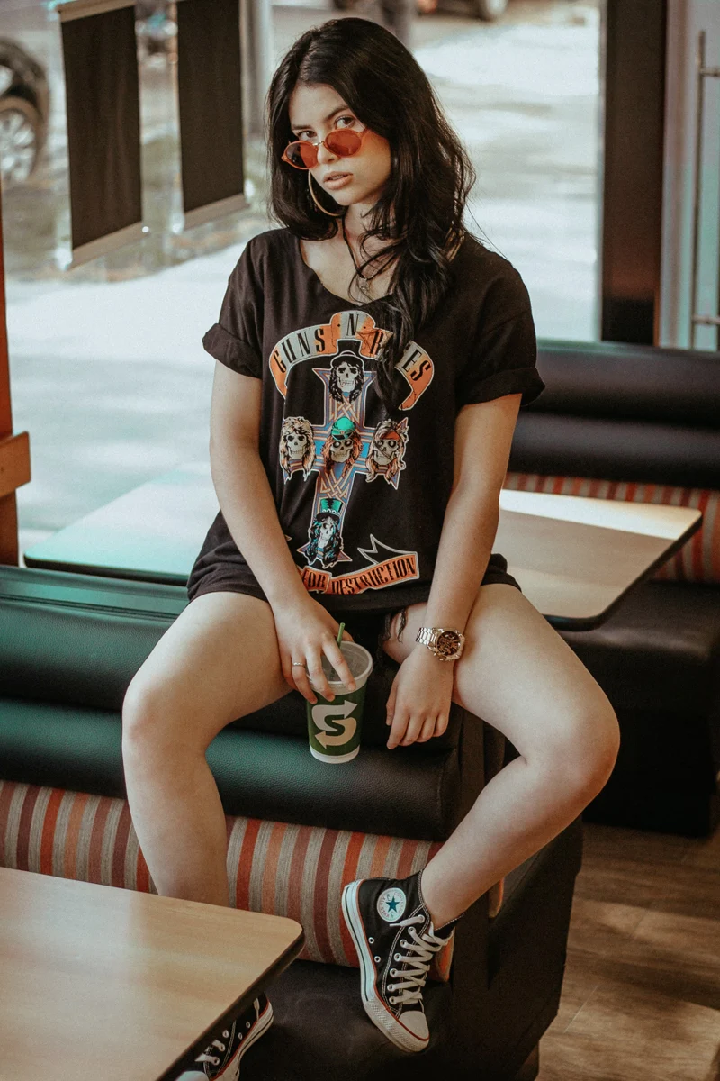 beautiful woman in a band tee is posing ina diner