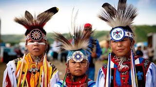 A picture of 3 First Nations children in traditional dress