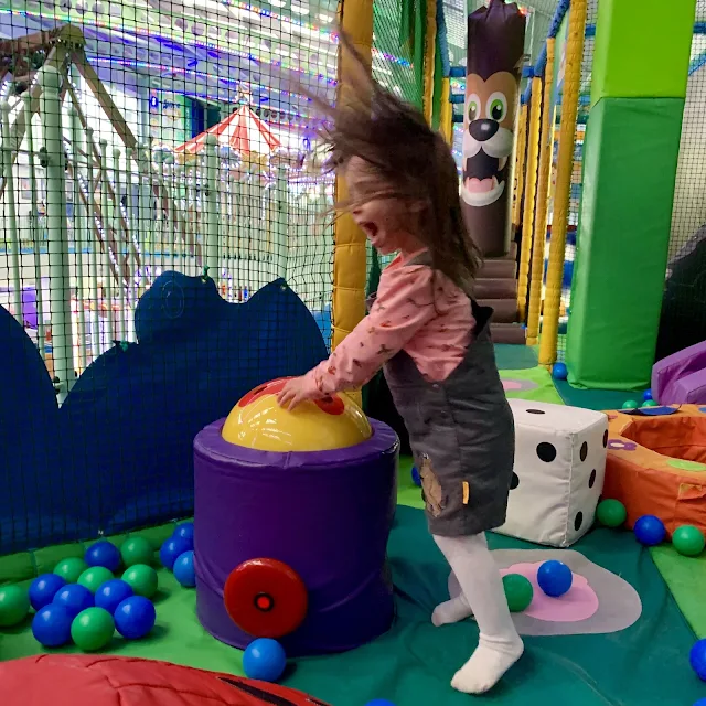 A preschooler playing with balls and air blowing machine in a soft play at Adventure Island