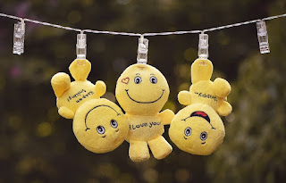3 yellow smiley plush toys hanging from a clothesline