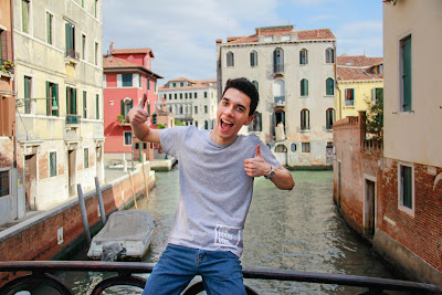 Man giving thumbs up sitting on road bridge buildings around