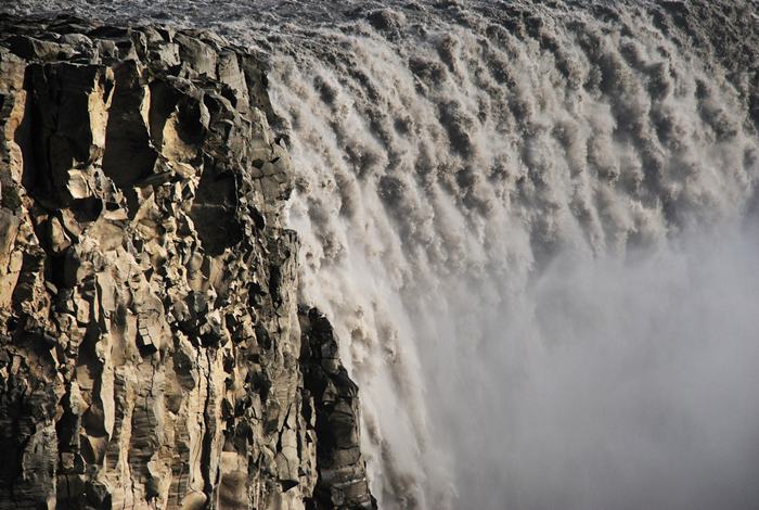 The waterfall Dettifoss is located in Vatnajökull National Park in Northeast Iceland, and reputed to be the most powerful waterfall in Europe. It is also the largest waterfall in Europe in terms of volume discharge, having an average water flow of 193 cubic meter per second. Its volume often increases, especially when the weather or volcanic activity prompts glacial melting on the Vatnajokull glacier icecap. The waterfall is so powerful that it makes the surrounding rocks vibrate, the vibrations can be felt by hand.