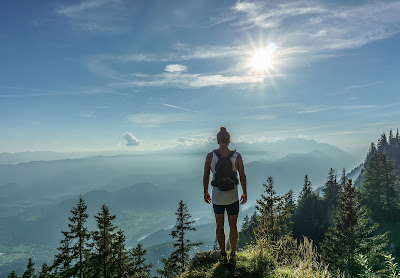 Lady in shorts looks down at hills from a mountain