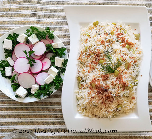 Persian lima bean rice with red radishes, feta cheese and curly parsley on a striped table runner