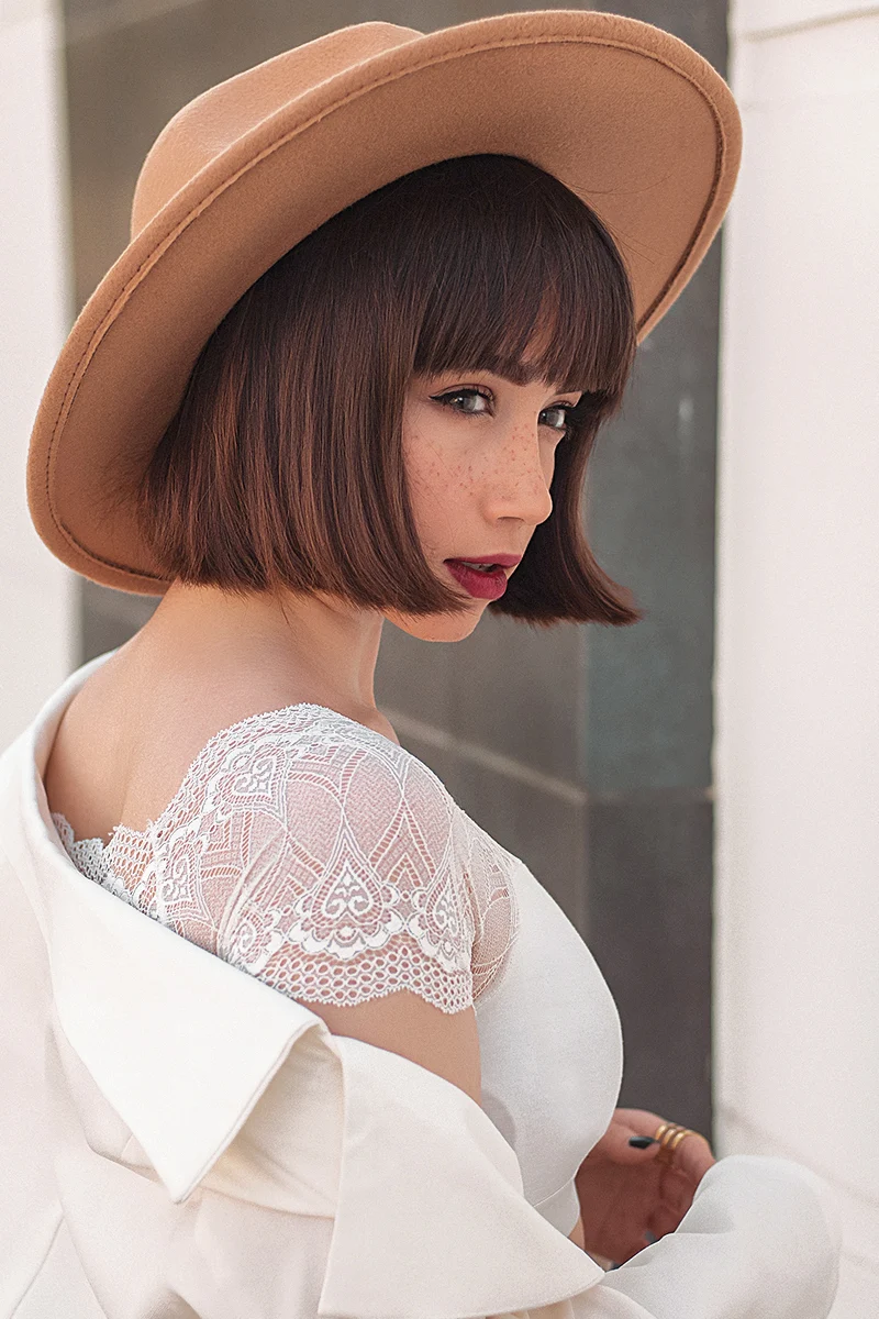 a portrait of a young womanon a balcony wearing large nude hat