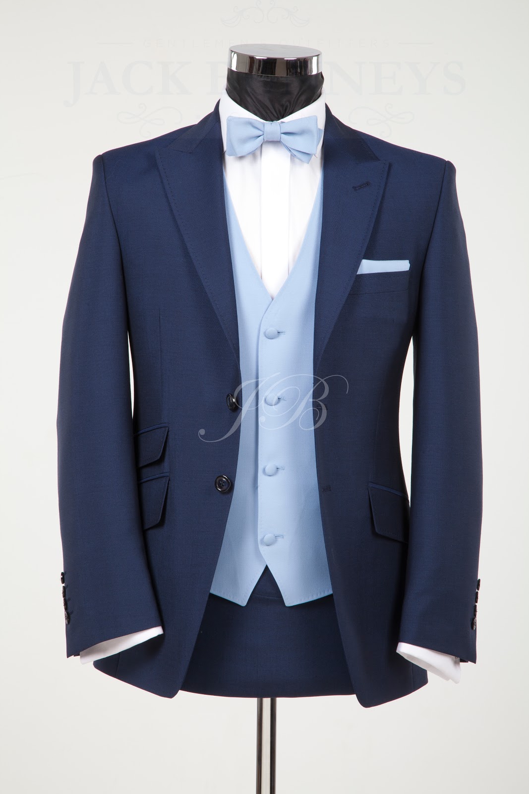 A man wearing a grey suit with a blue and white striped bow tie
