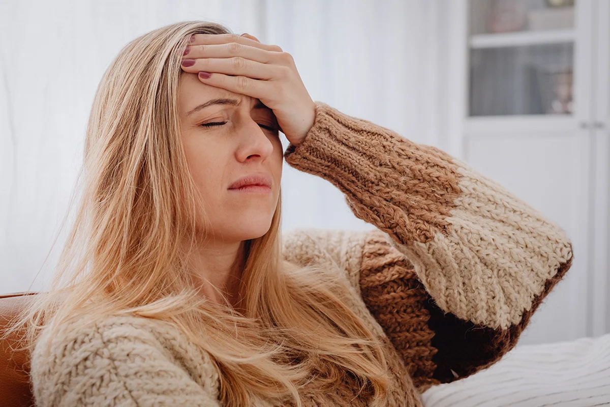 woman on a sofa holds her head in her hands