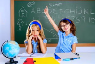 Students in a classroom raising hands.