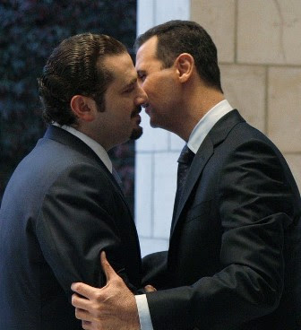 bashar leans slightly forward and whispers softly into hariri's ear 