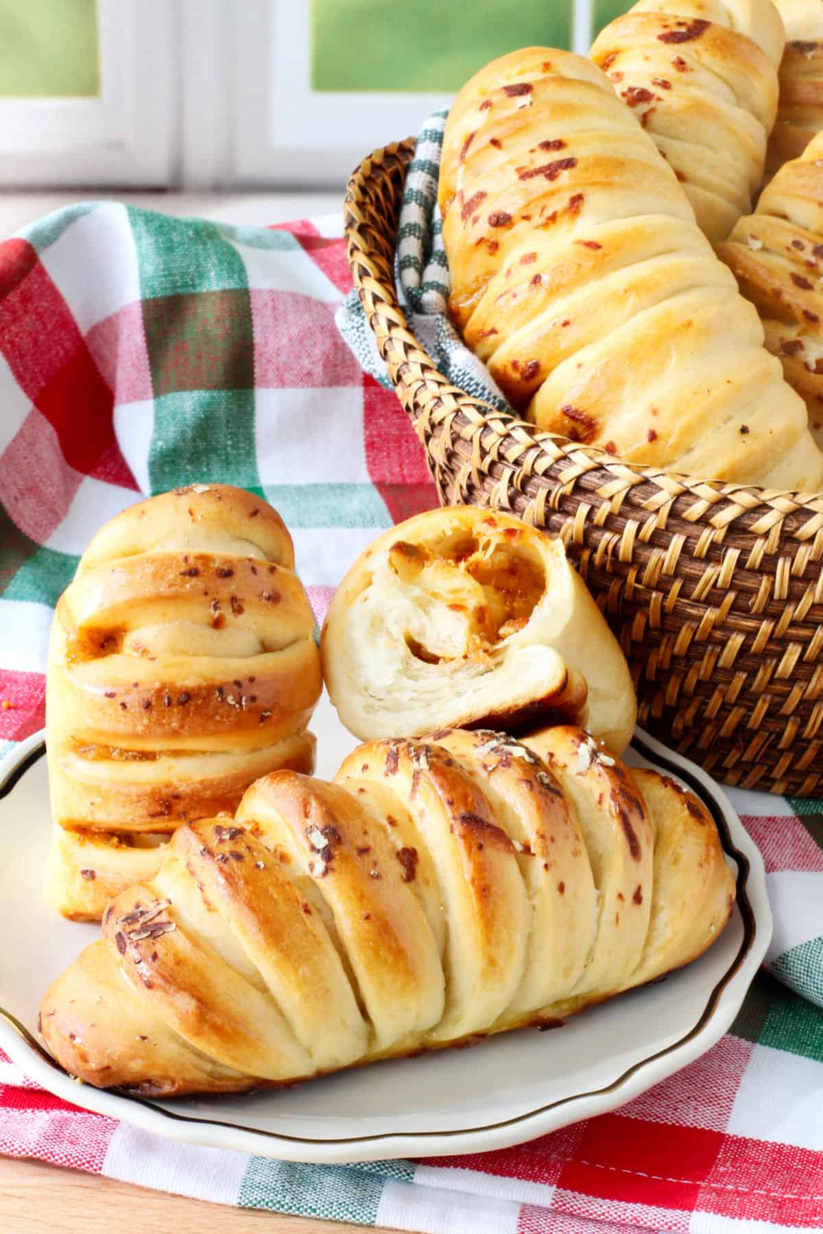 Sambal Oelek Milk Bread Buns on a plate showing the interior and a basket in the back.