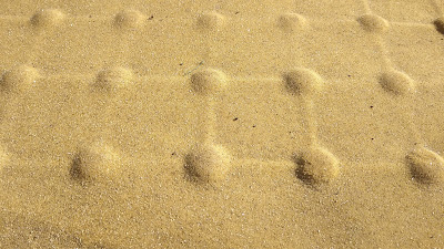 A close view of yellowish tactile paving blisters in a grid pattern.