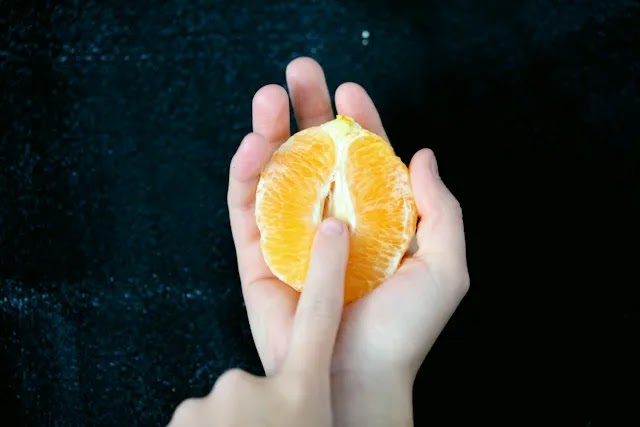 Placing finger on half orange fruit