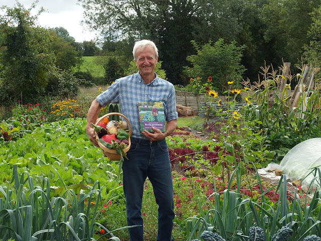 Charles Dowding proudly poses at Homeacres with a healthy basket of produce and his latest book