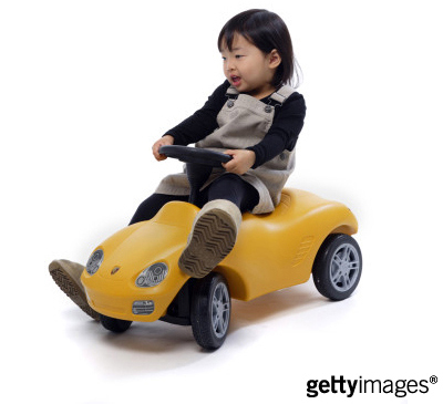 asian girl about age 4 driving a plastic toy car