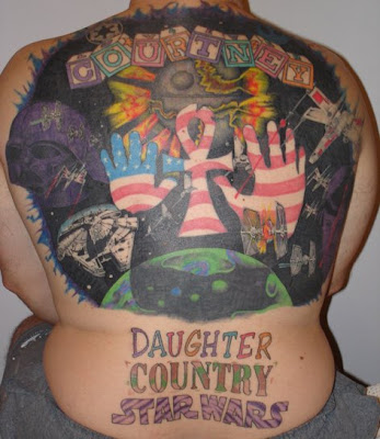 A cute lower back tattoo reading 'Country Girl' with a revolver on either