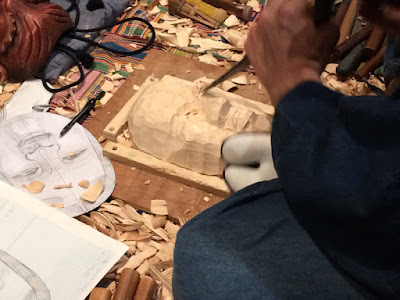 Close up of a chisel being used to carve a wooden mask