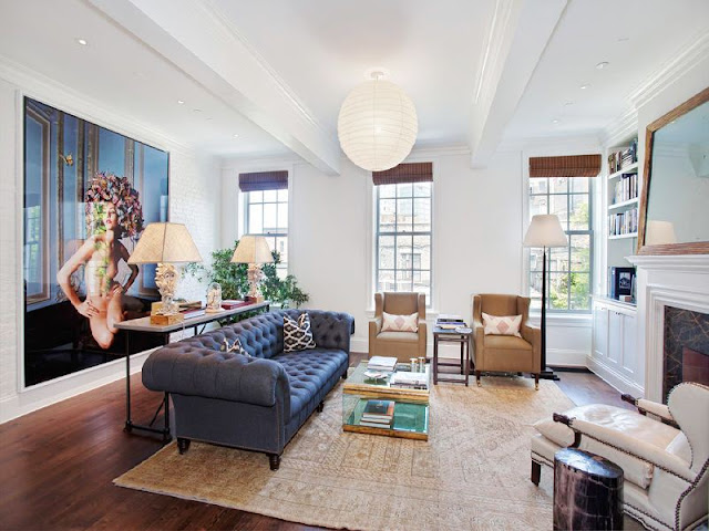 living room with black upholstered sofa, two brown armchairs, one white upholstered arm chair, a marble fireplace with a large mirror on the mantel and a white painted brick walls