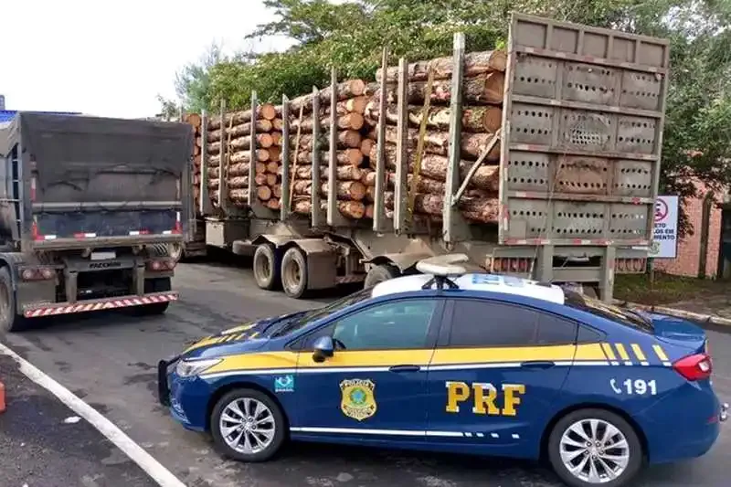 Viatura da PRF estacionada atrás de duas carretas com excesso de carga