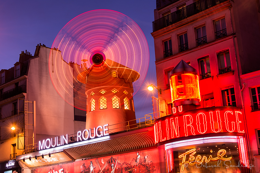 Monmarte area of Paris, Moulin Rouge at night with spinning windmill.