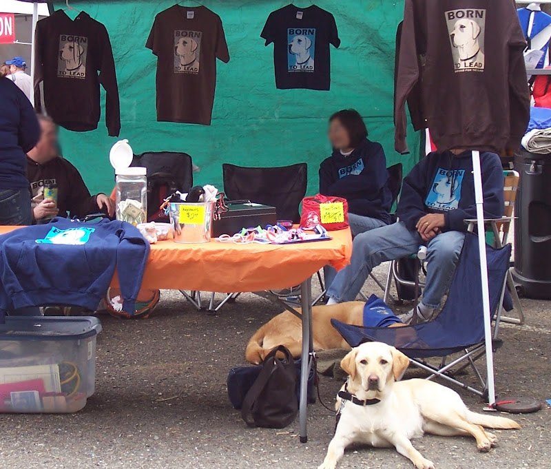 cabana laying on the ground in front of a canopy tent that has people sitting in it and Born to Lead shirts hanging all around