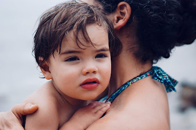 Picture on a Mum and child in swim ware. Mum is holding the shy child in her arms. How Should Swim Teachers Connect With A Shy Child?