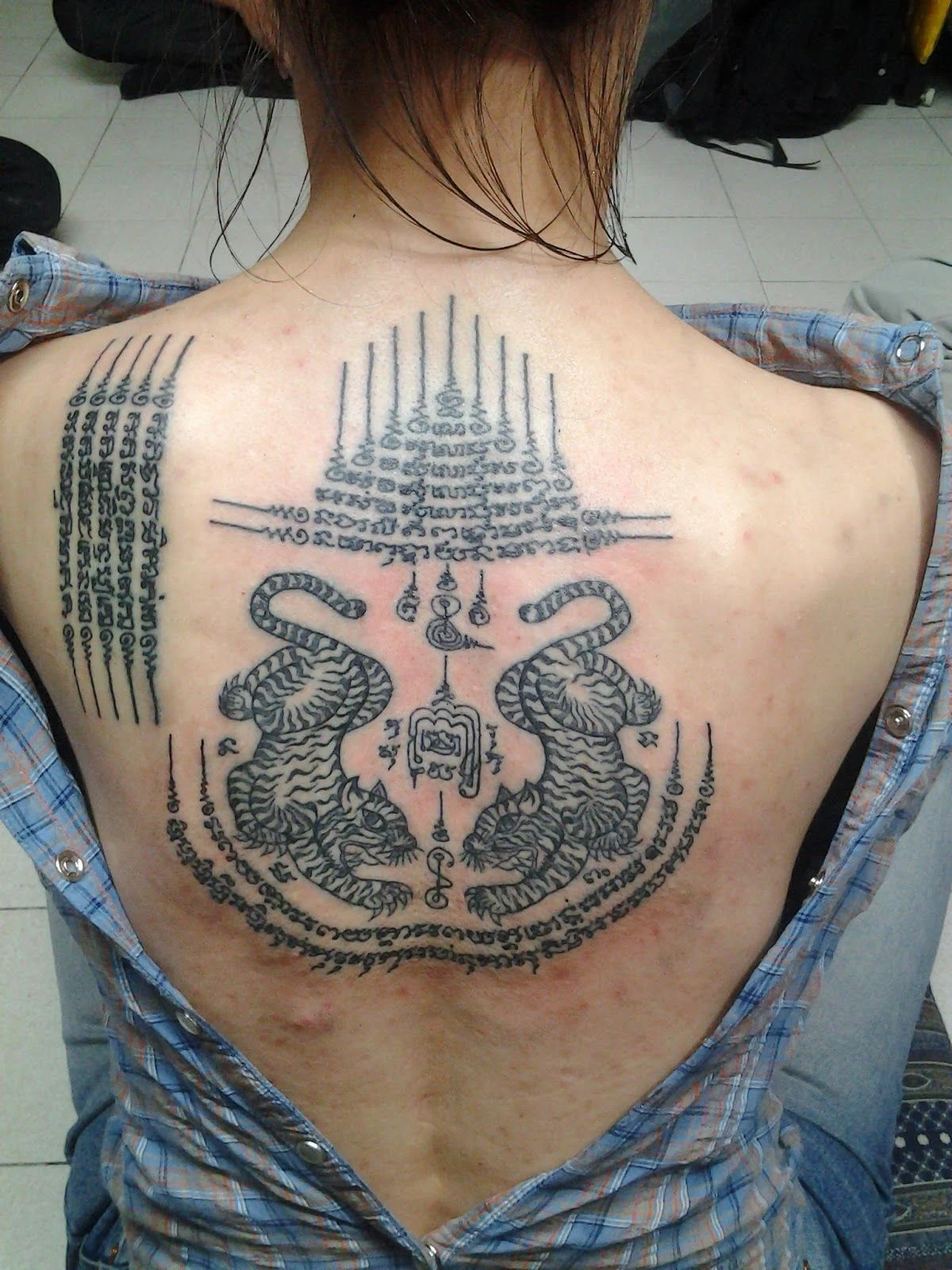 Una modelo con tatuajes Sak-Yant de dos tigres en la espalda