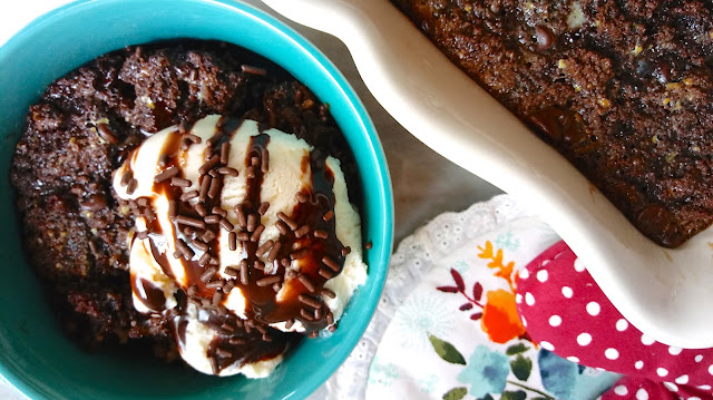 a serving of Chocolate Cupcake Bread Pudding topped with ice cream, chocolate sauce, and sprinkles next to the Chocolate Cupcake Bread Pudding casserole