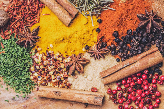 A plethora of autumn spices including cinnamon and turmeric spread out on a table