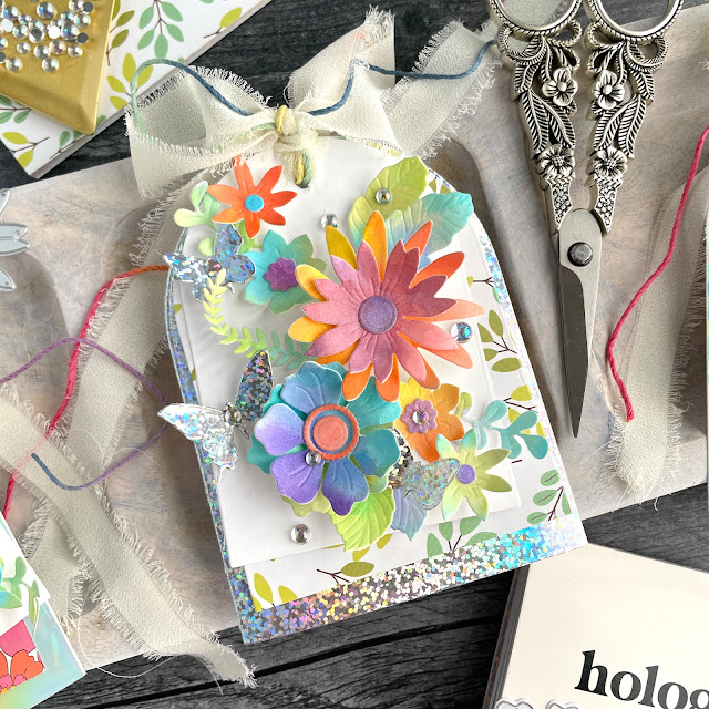 Floral Tags created with: Scrapbook.com sunny lane florals, nested A2 arches, butterflies 2 die set, holographic paper pad, sunny lane paper pad; Tim Holtz distress inks; Prima Art Philosophy watercolor paper pad; Pinkfresh iridescent clear drops
