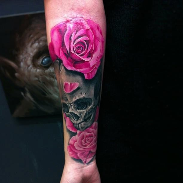 Vivid colors dark skull with pink roses forearm tattoo