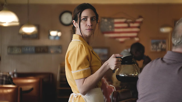 A woman working at a diner serves coffee