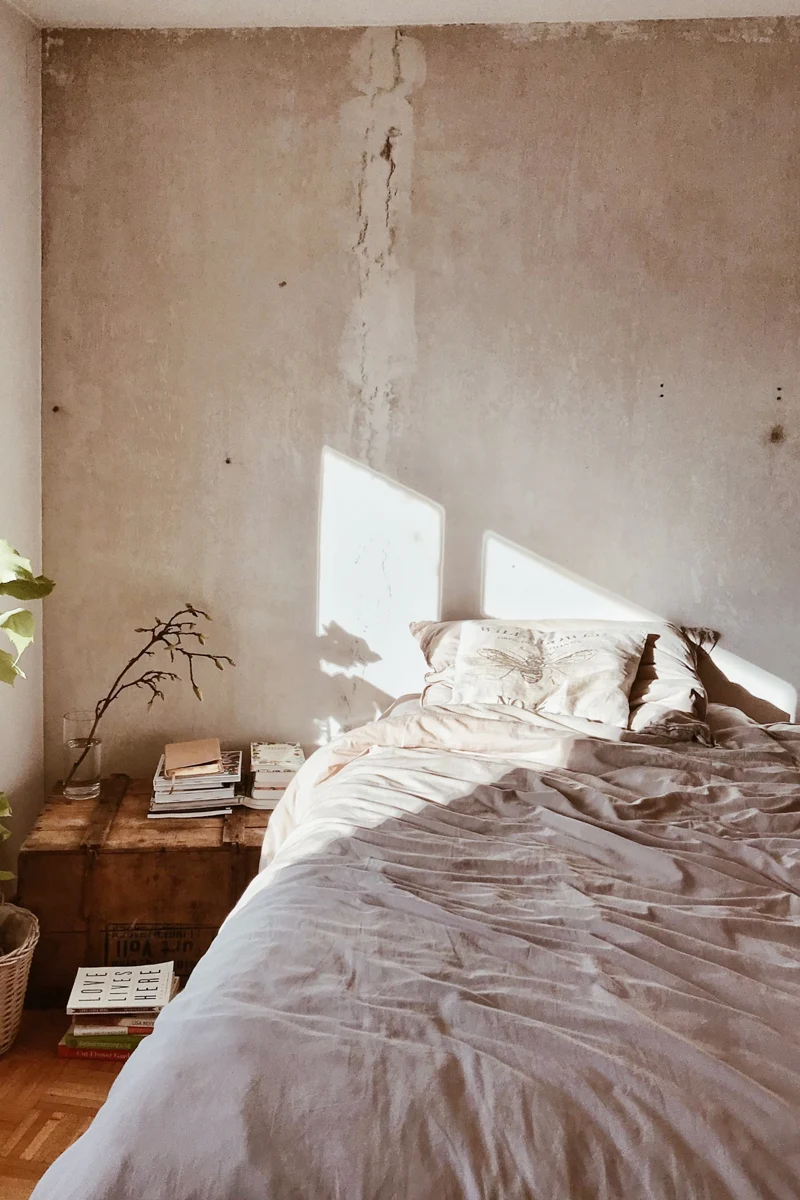 small bedroom with natural light falling on a bed