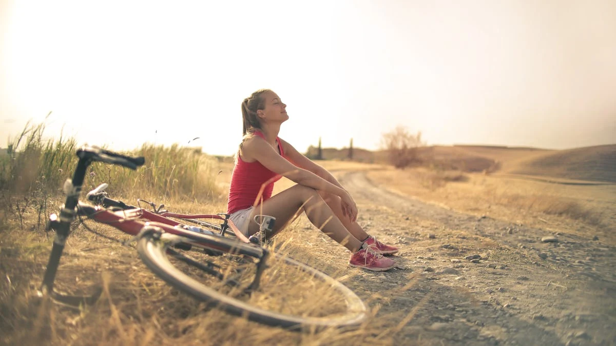 Sportive Woman with Bicycle Resting on Countryside Road in Sunlight