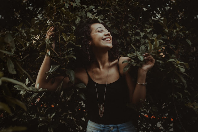 Pretty brunette girl posing in front of trees.