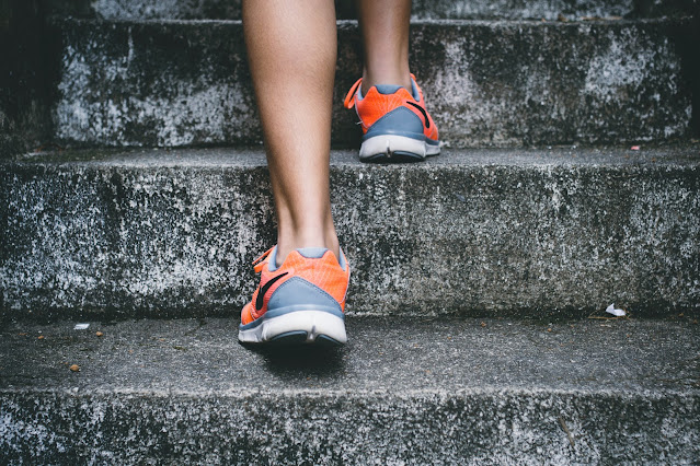 View of legs and feet wearing trainers walking up steps:Photo by Bruno Nascimento on Unsplash