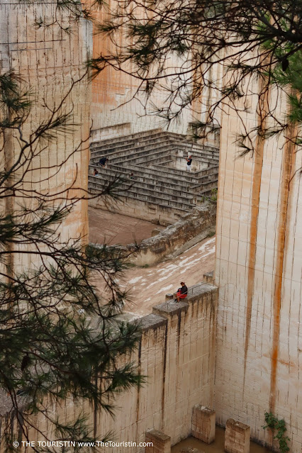 Two people wandering independently through the remnants of giant sandstone quarries.