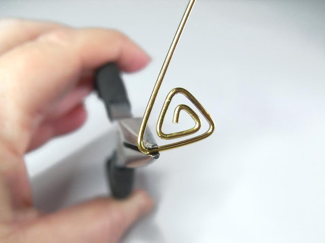 Using chain nose pliers to bend the wire at a 60° angle.